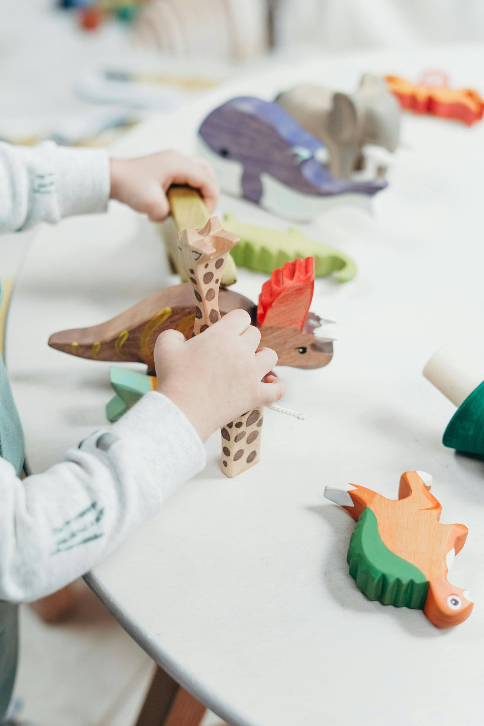 A child's hands playing with wooden dinosaurs
