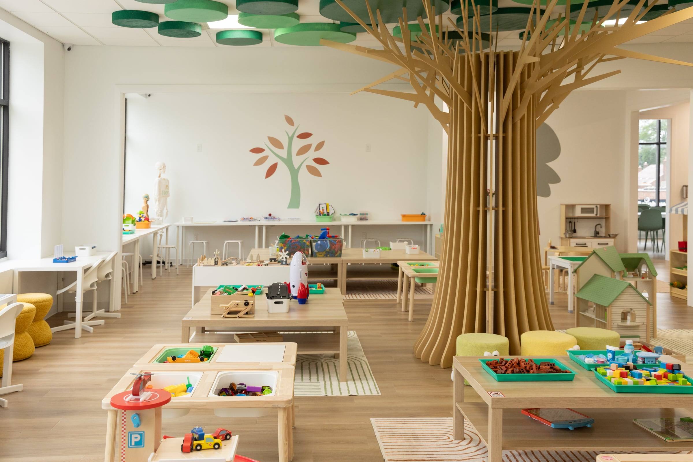 The play room with the wooden tree, play tables and toys